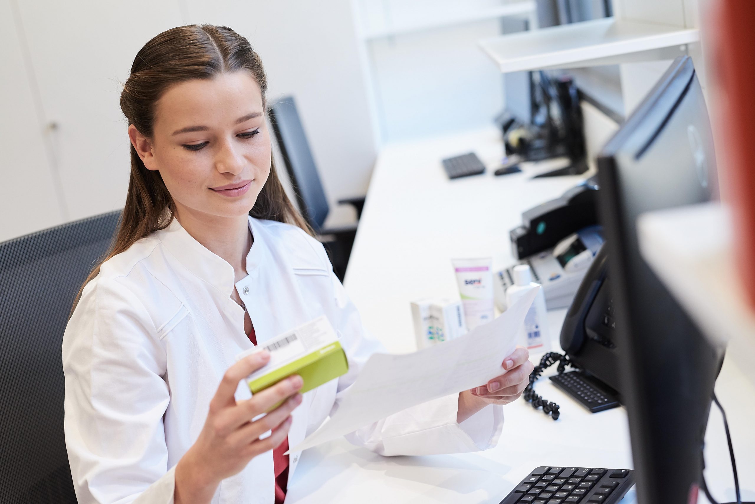 PTA mit einem Medikament in der Hand vor einem Computer